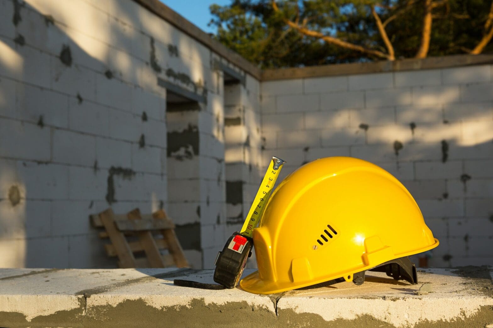Construction hardhat and measuring tape measure on the window of a house under construction